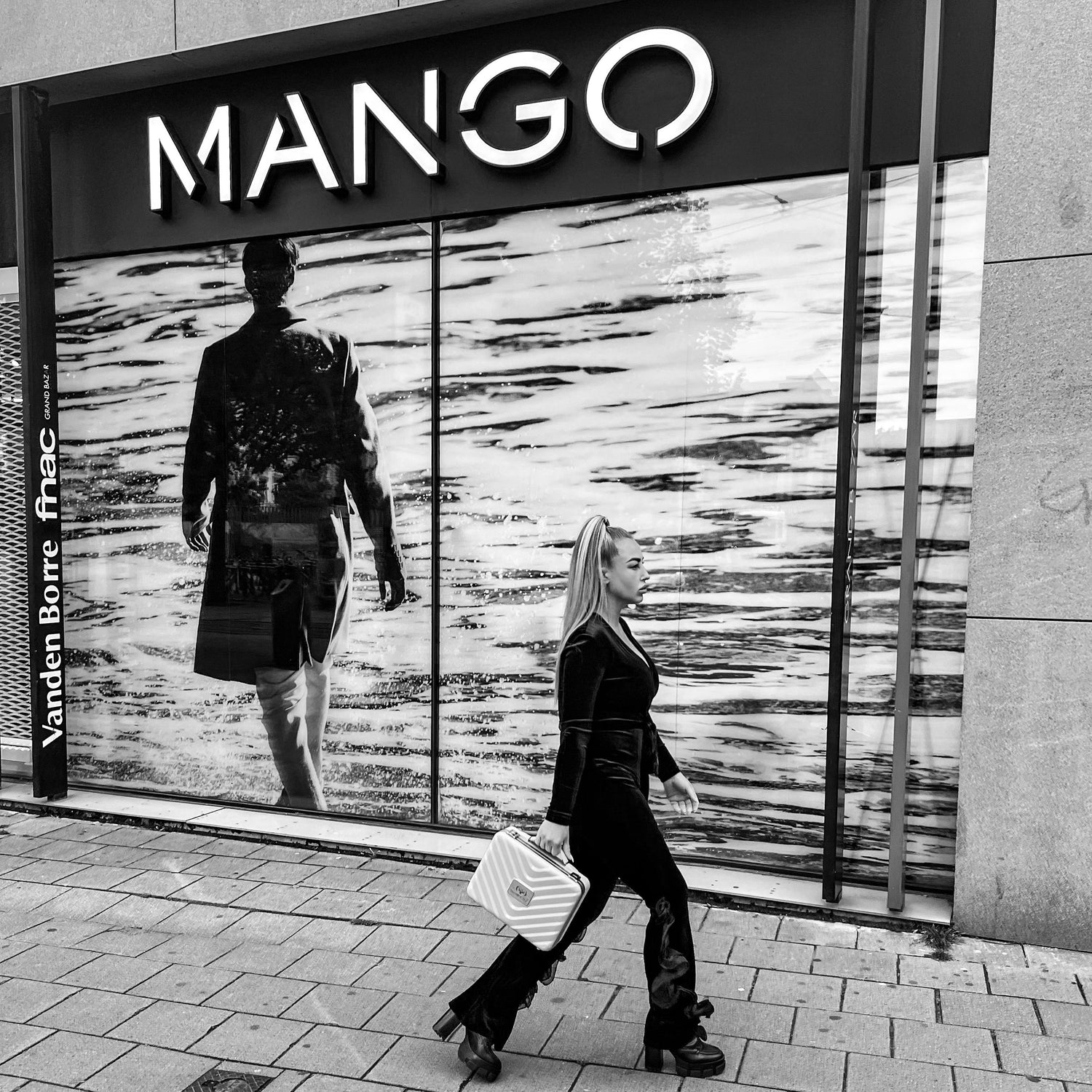 Woman walking in front of Mango store in a stylish outfit, holding a handbag